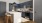 Modern kitchen in Oklahoma City apartments featuring blue cabinets, white countertops, a central island with wooden stools, stainless steel appliances, and a tiled backsplash. A pendant light hangs gracefully above the island.